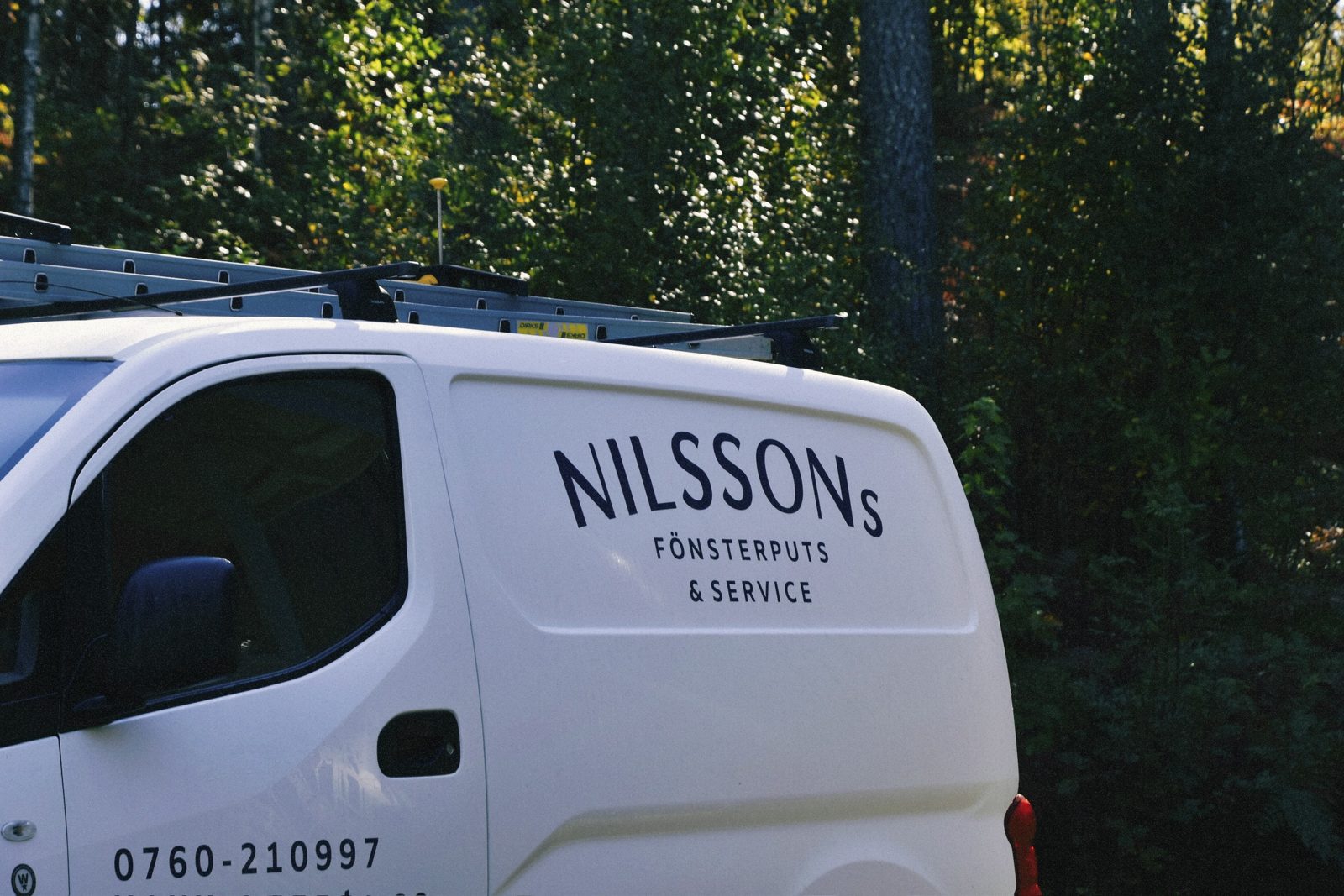 Nilssons vita servicebil med stegar på taket